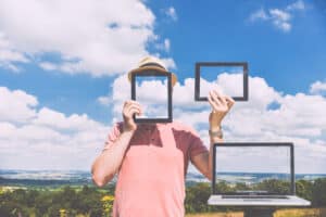 Man holding tablets reflecting the cloudy sky.