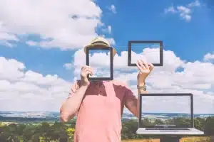 Man holding tablets reflecting the cloudy sky.
